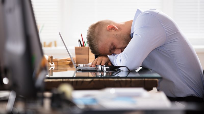 Close-up Of A Businessman Sleeping Over The Office Desk With Laptop